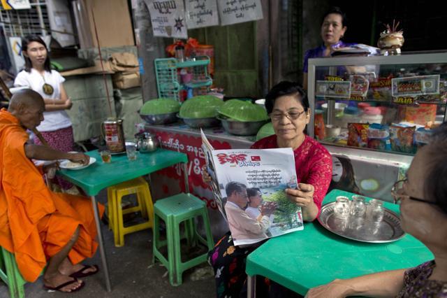 A woman reads a copy of "D-Wave a newspaper featuring Myanmar's opposition leader Aung San Suu Kyi and patron Tin Oo on it's cover in a street restaurant in Yangon, Myanmar. (AP) A woman reads a copy of "D-Wave a newspaper featuring Myanmar's opposition leader Aung San Suu Kyi and patron Tin Oo on it's cover in a street restaurant in Yangon, Myanmar. (AP)