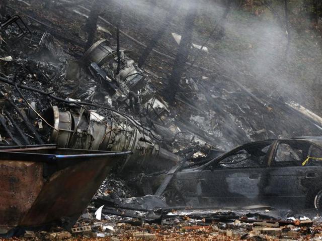 A charred car and aircraft debris smoulder where authorities say a small business jet crashed into an apartment building in Akron, Ohio. (AP) A charred car and aircraft debris smoulder where authorities say a small business jet crashed into an apartment building in Akron, Ohio. (AP)