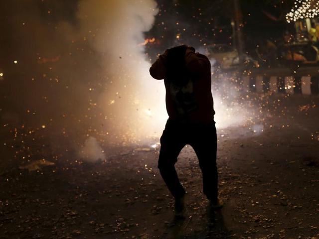 A man tries to protect himself from firecrackers while celebrating the Diwali in New Delhi on November 11, 2015. The fire department said it received 290 calls related to minor fire incidents on Diwali in the national capital. (REUTERS) A man tries to protect himself from firecrackers while celebrating the Diwali in New Delhi on November 11, 2015. The fire department said it received 290 calls related to minor fire incidents on Diwali in the national capital. (REUTERS)