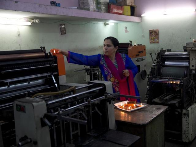 A woman places a lamp on a machine during Diwali in New Delhi. (AP)