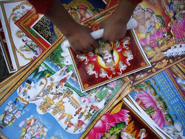 A Nepalese street vendor rolls a picture of Hindu goddess Lakshmi as he sells them during Tihar festival in Katmandu, Nepal, Thursday, Oct. 23, 2014. Hindus decorate their houses and worship Lakshmi, the goddess of wealth, during this festival of lights. (AP)