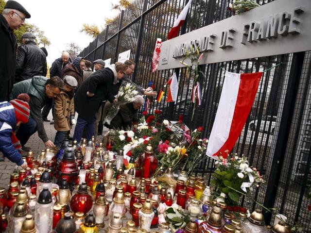 People light candles and put flowers in front of the French embassy in Warsaw in tribute to victims of Paris attacks.(REUTERS)