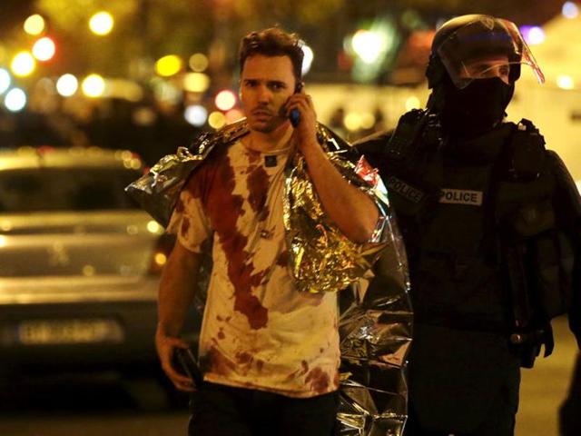 A French policeman assists a blood-covered victim near the Bataclan concert hall following attacks in Paris.(Reuters)