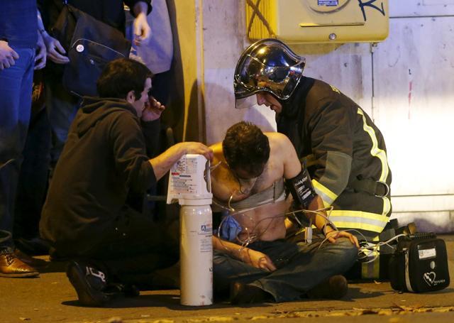French fire brigade members aid an injured individual near the Bataclan concert hall following fatal shootings in Paris. (Reuters)