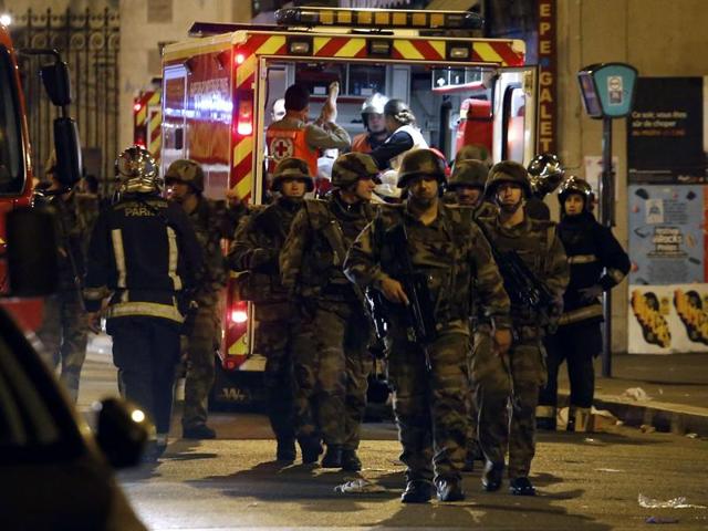 Soldiers walk in front of an ambulance as rescue workers evacuate victims near La Belle Equipe, rue de Charonne. (AFP)