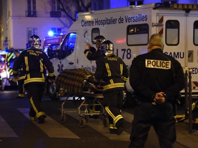 Firefighters evacuate an injured person near the Bataclan concert hall in central Paris. (AFP)