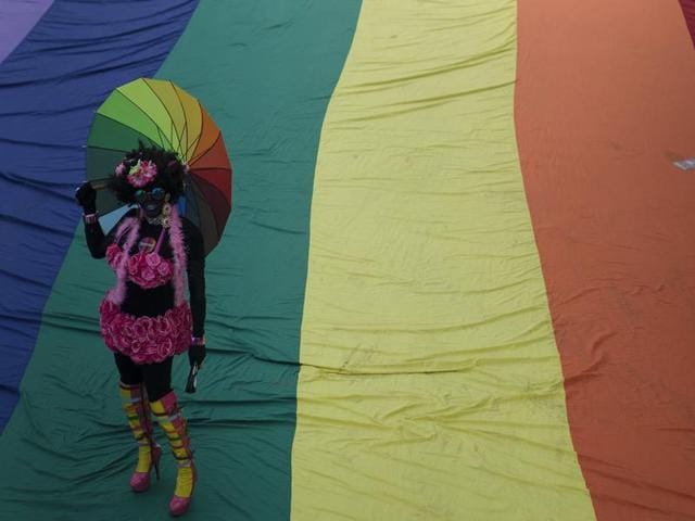 A man poses as he stands on a giant gay movement flag during the Gay Pride Parade in Rio de Janeiro, Brazil on Sunday. (AP)