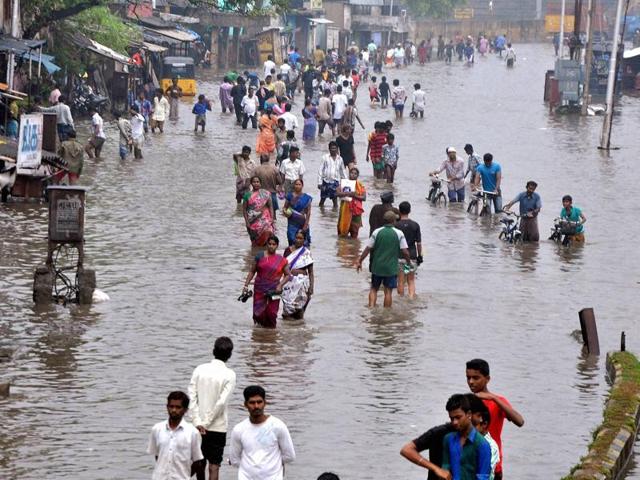 People wade through a waterlogged road following heavy rains at Vyasarpadi in Chennai. (PTI) People wade through a waterlogged road following heavy rains at Vyasarpadi in Chennai. (PTI)