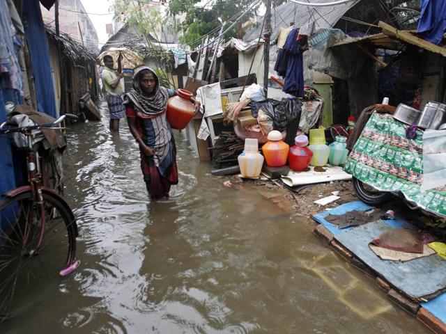 Woman carries a vessel of water at a slum dwelling as it rains in Chennai. (AP) Woman carries a vessel of water at a slum dwelling as it rains in Chennai. (AP)