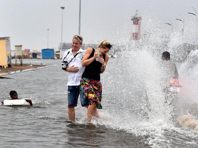 Foreigners trying to move away as a motorcycle splashes water at Marina Beach in Chennai on Saturday. (PTI) Foreigners trying to move away as a motorcycle splashes water at Marina Beach in Chennai on Saturday. (PTI)