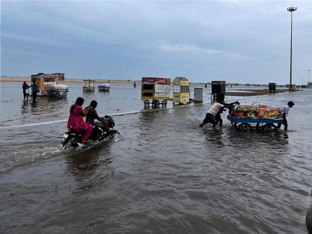 Vendors push a cart on the waterlogged Marina Beach in Chennai. (PTI) Vendors push a cart on the waterlogged Marina Beach in Chennai. (PTI)