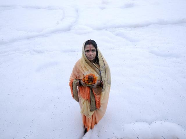 Hindu devotee offers prayers during Chhath Puja on the banks of river Yamuna, in Noida. (Burhaan Kinu /HT Photo)