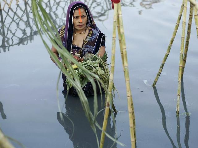 Hindu devotees offer prayers during Chhath Puja on the banks of river Yamuna, in Noida, India, on Tuesday, November 17, 2015. Devotees pay obeisance to both the rising and the setting sun during the Chhath Festival, expressing thanks and seeking the blessings of the forces of nature, mainly the sun and rivers. (Burhaan Kinu / HT Photo)