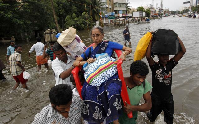 Rescue workers carry an elderly woman to safety at a residential area that was water-logged following heavy rains in Chennai, Tamil Nadu. (AP Photo)