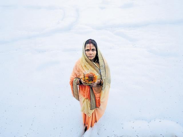 A woman offers prayers to the Sun God on the banks of the Yamuna in Noida. (BURHAAN KINU/HT PHOTO) A woman offers prayers to the Sun God on the banks of the Yamuna in Noida. (BURHAAN KINU/HT PHOTO)