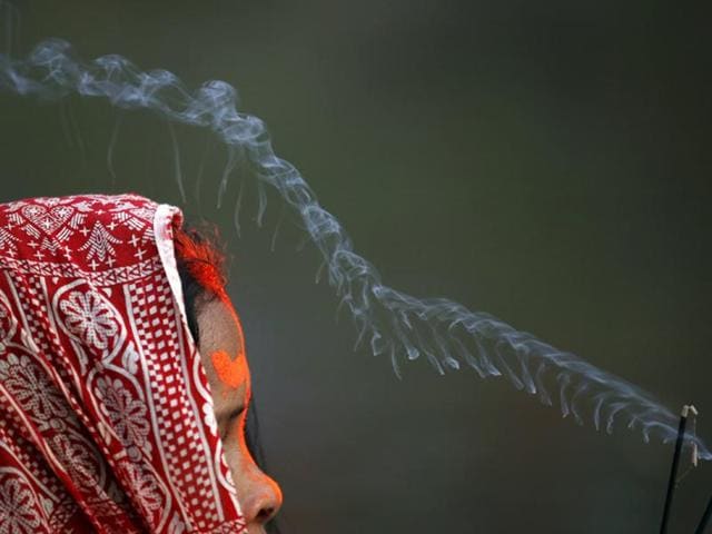 Smoke rises from the burning incense as a devotee offers prayer to the setting sun. (Navesh Chitrakar/Reuters Photo)