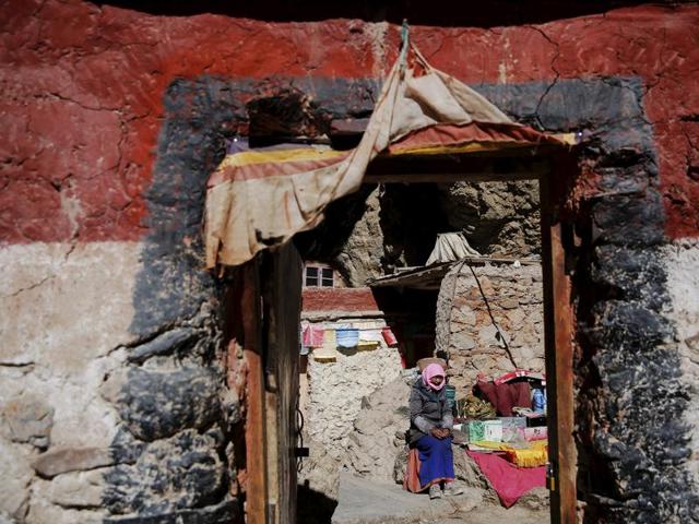 A Tibetan woman sits in front of a house built in a rock at the shores of Namtso lake. (REUTERS)