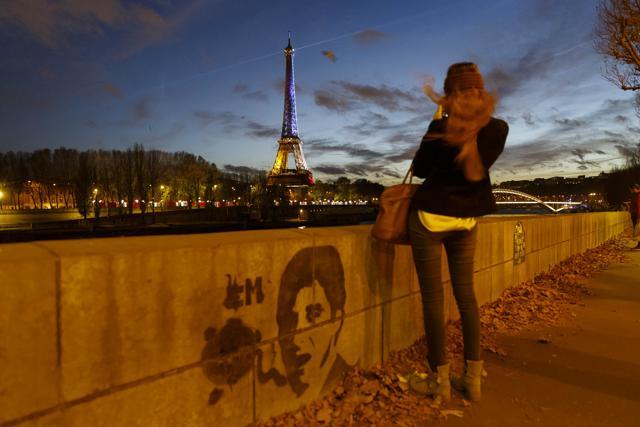 A girl takes a picture from the banks of the River Seine of the illuminated Eiffel Tower in the French national colours in honour of the victims of the terrorist attacks last Friday, in Paris. (AP Photo) A girl takes a picture from the banks of the River Seine of the illuminated Eiffel Tower in the French national colours in honour of the victims of the terrorist attacks last Friday, in Paris. (AP Photo)
