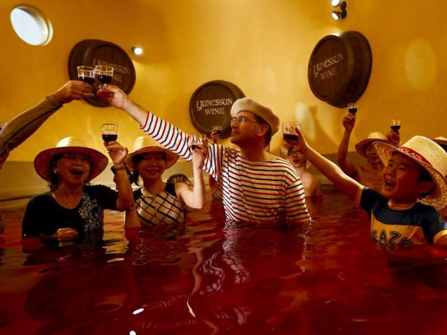People clink wine glasses as they stand in a hot bath with coloured water representing wine at the Hakone Kowaki-en Yunessun spa resort, Tokyo. (REUTERS)