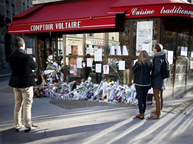 People stop to look at flowers, candles and messages in tribute to victims in front of the Comptoir Voltaire cafe, one of the sites of the deadly attacks in Paris. (REUTERS) People stop to look at flowers, candles and messages in tribute to victims in front of the Comptoir Voltaire cafe, one of the sites of the deadly attacks in Paris. (REUTERS)
