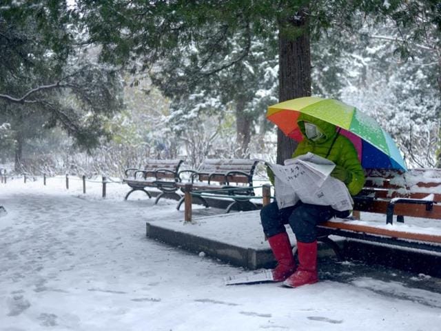 A man wearing mask reads the newspaper at a park near the Forbidden City during a snowfall in Beijing on November 22, 2015. (AFP) A man wearing mask reads the newspaper at a park near the Forbidden City during a snowfall in Beijing on November 22, 2015. (AFP)