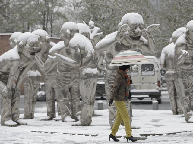 A woman walks past the sculpture by Chinese artist Yue Minjun during snowfall in Beijing, China, November 22, 2015. (REUTERS) A woman walks past the sculpture by Chinese artist Yue Minjun during snowfall in Beijing, China, November 22, 2015. (REUTERS)