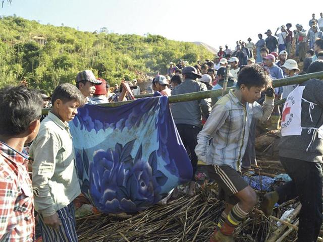 Myanmar Red Cross workers and people carry victims at a landslide affected area at Phakant jade mine, Kachin State. (AP) Myanmar Red Cross workers and people carry victims at a landslide affected area at Phakant jade mine, Kachin State. (AP)