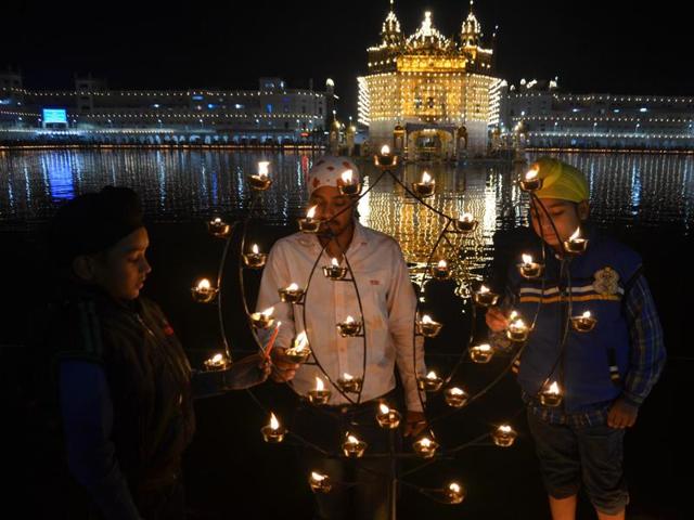 Children lighting candles at a lit-up Golden Temple in Amritsar on Wednesday. (Sameer Sehgal/HT Photo)