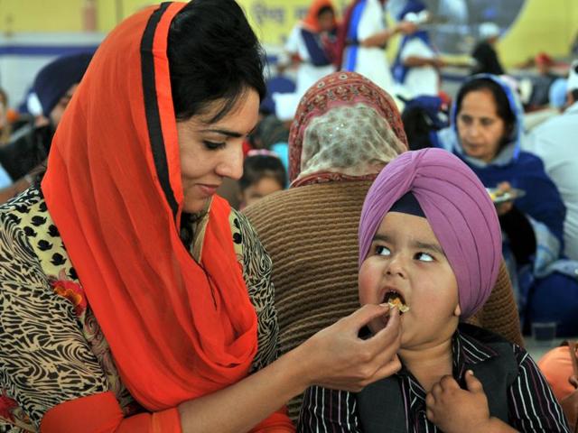 A mother offering ‘langar’ to her son during Gurpurab celebrations to mark the Guru Nanak Dev’s birth anniversary in Jalandhar on Wednesday. (Pardeep Pandit/HT Photo)