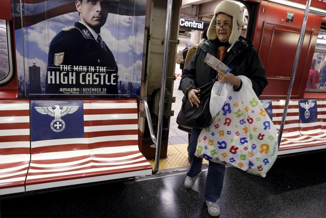 Passengers board a 42nd Street Shuttle subway train, wrapped with advertising for the Amazon series The Man in the High Castle in the Manhattan borough of New York, November 24, 2015. (REUTERS) Passengers board a 42nd Street Shuttle subway train, wrapped with advertising for the Amazon series The Man in the High Castle in the Manhattan borough of New York, November 24, 2015. (REUTERS)