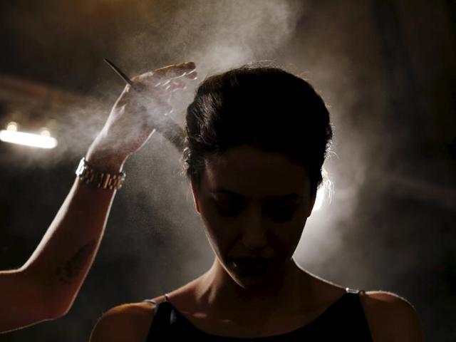 A hairdresser sprays hair spray on a model backstage, creating a stunning effect for the photographer to use. (REUTERS)