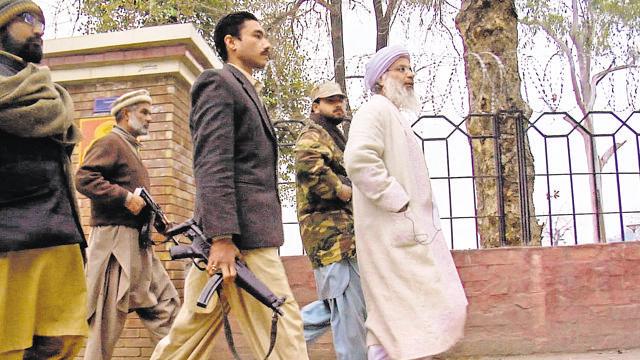 Armed guards walk with Aziz within the mosque premises. Though he was fired by the Pakistan government, he continues to serve as head cleric.