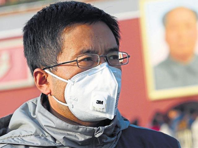 A man wearing a mask walks past a portrait of Mao at the Tiananmen Gate in Beijing on Sunday. (Reuters) A man wearing a mask walks past a portrait of Mao at the Tiananmen Gate in Beijing on Sunday. (Reuters)