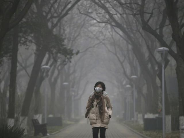 A woman wearing a mask walks as smog covers China's capital Beijing. (REUTERS Photo)