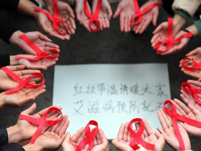 This picture taken on November 30, 2015 shows volunteers holding red ribbons above a piece of paper written in Chinese that reads ''Red ribbons bring warmth to everyone to prevent AIDS" during an event for World Aids Day in Chongqing. (AFP) This picture taken on November 30, 2015 shows volunteers holding red ribbons above a piece of paper written in Chinese that reads ''Red ribbons bring warmth to everyone to prevent AIDS" during an event for World Aids Day in Chongqing. (AFP)