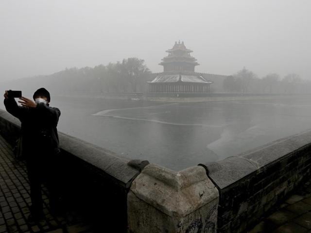A man wearing a mask to protect himself from pollutants takes a selfie near the Turret of the Forbidden City on a heavily polluted day in Beijing. (AP Photo)