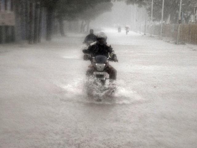 A man rides his motorbike through a flooded road during heavy rain in Chennai.(REUTERS)