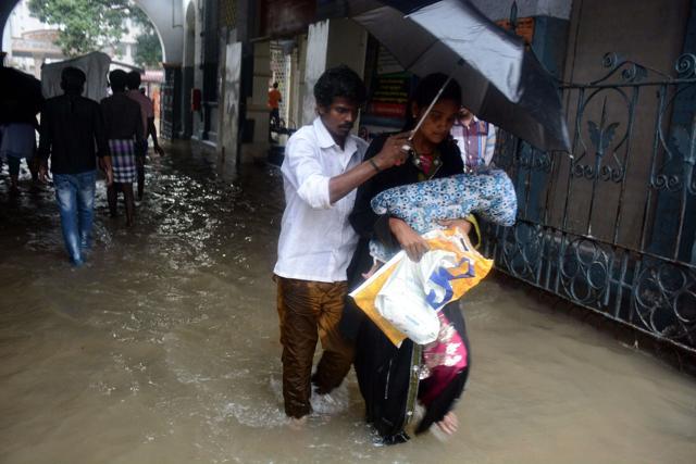 A couple shelter under an umbrella as they walk with their child through an inundated Egmore Hospital in Chennai. (AFP) A couple shelter under an umbrella as they walk with their child through an inundated Egmore Hospital in Chennai. (AFP)