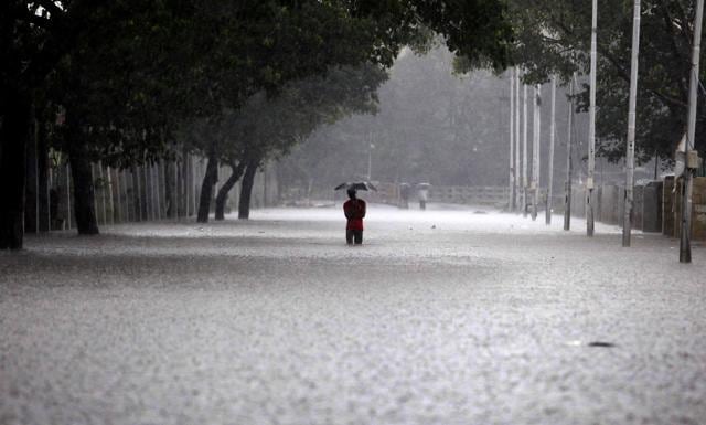 A man shelters under an umbrella as he walks through water in Chennai. (AFP) A man shelters under an umbrella as he walks through water in Chennai. (AFP)