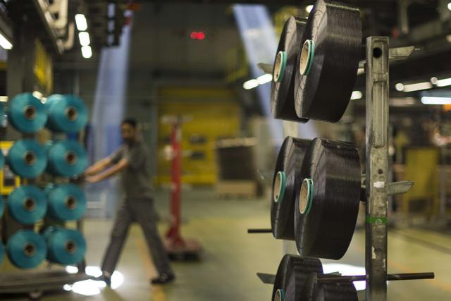 An employee pulls a trolley behind spools of yarn made from plastic waste at the yarn processing plant. (AFP) An employee pulls a trolley behind spools of yarn made from plastic waste at the yarn processing plant. (AFP)