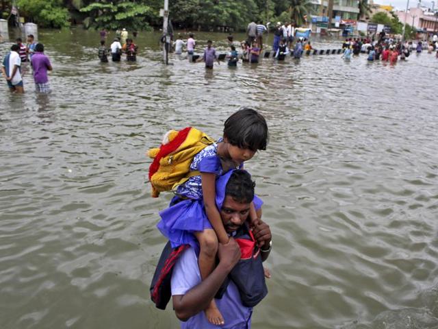 A man carries a girl through a flooded road in Chennai. The heaviest rainfall in over a century caused massive flooding across Tamil Nadu. (REUTERS)