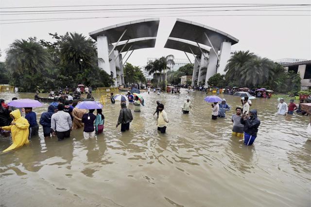 People wade through a waterlogged road following heavy rains in Chennai. (PTI) People wade through a waterlogged road following heavy rains in Chennai. (PTI)
