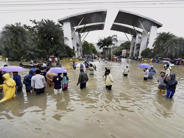 People wade through waterlogged roads after heavy rains inundated several areas, at Porur in Chennai. (PTI Photo)