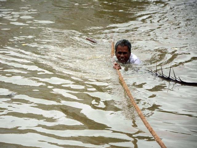 A man clings to a rope as he makes his way through floodwaters in Chennai. (AFP)