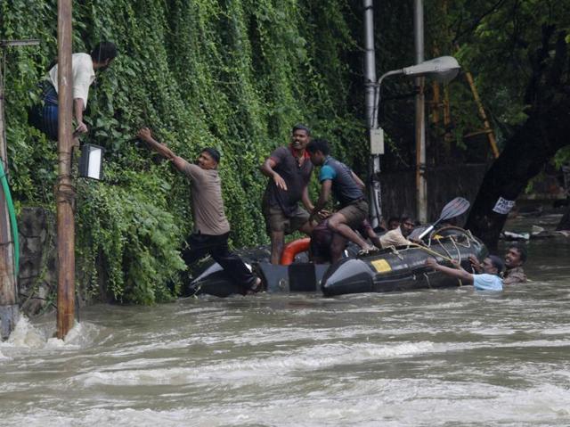 Rescuers try to evacuate a man stranded in the floods by an over-flowing Adyar River in Chennai. (AP)
