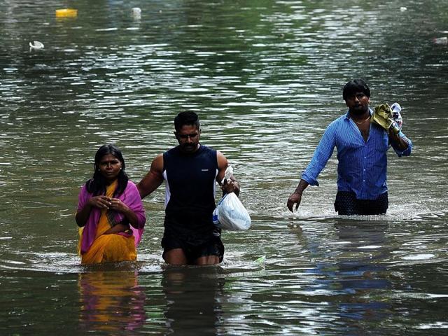 A man leads an elderly woman past a flooded street in a residential area in Chennai. (AP)