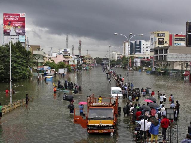 People stand on a flooded road in Chennai. The heaviest rainfall in over a century caused massive flooding across Tamil Nadu, driving thousands from their homes, shutting auto factories and paralysing the airport in the state capital Chennai. (Reuters Photo)