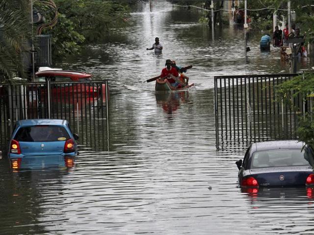 People travel on a boat as they move to safer places through a flooded road in Chennai. The heavy rains drove thousands from their homes, shutting auto factories and paralysing the airport. (REUTERS)