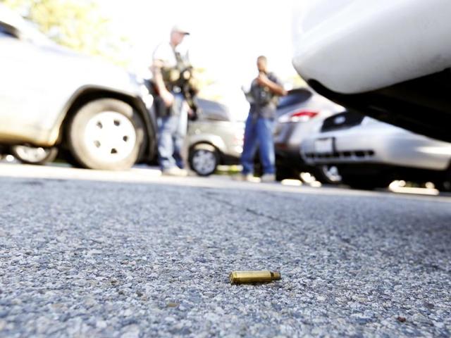 A used cartridge lies on the ground as police officers secure the area. (REUTERS)