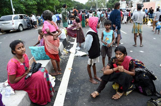 People sitting on the road after they were rescued from a flooded locality. (PTI Photo)